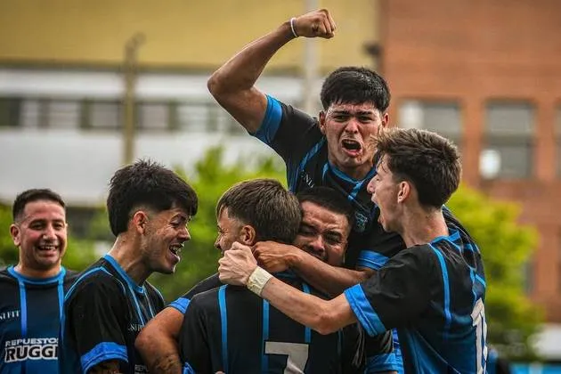 Jugadores del plantel de mayores del Club Universitario de Berisso festejando un gol abrazados